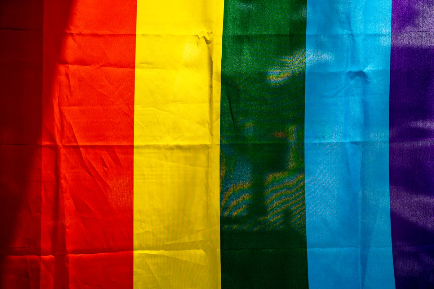 A close-up shows the fabric and stripes of a rainbow flag.