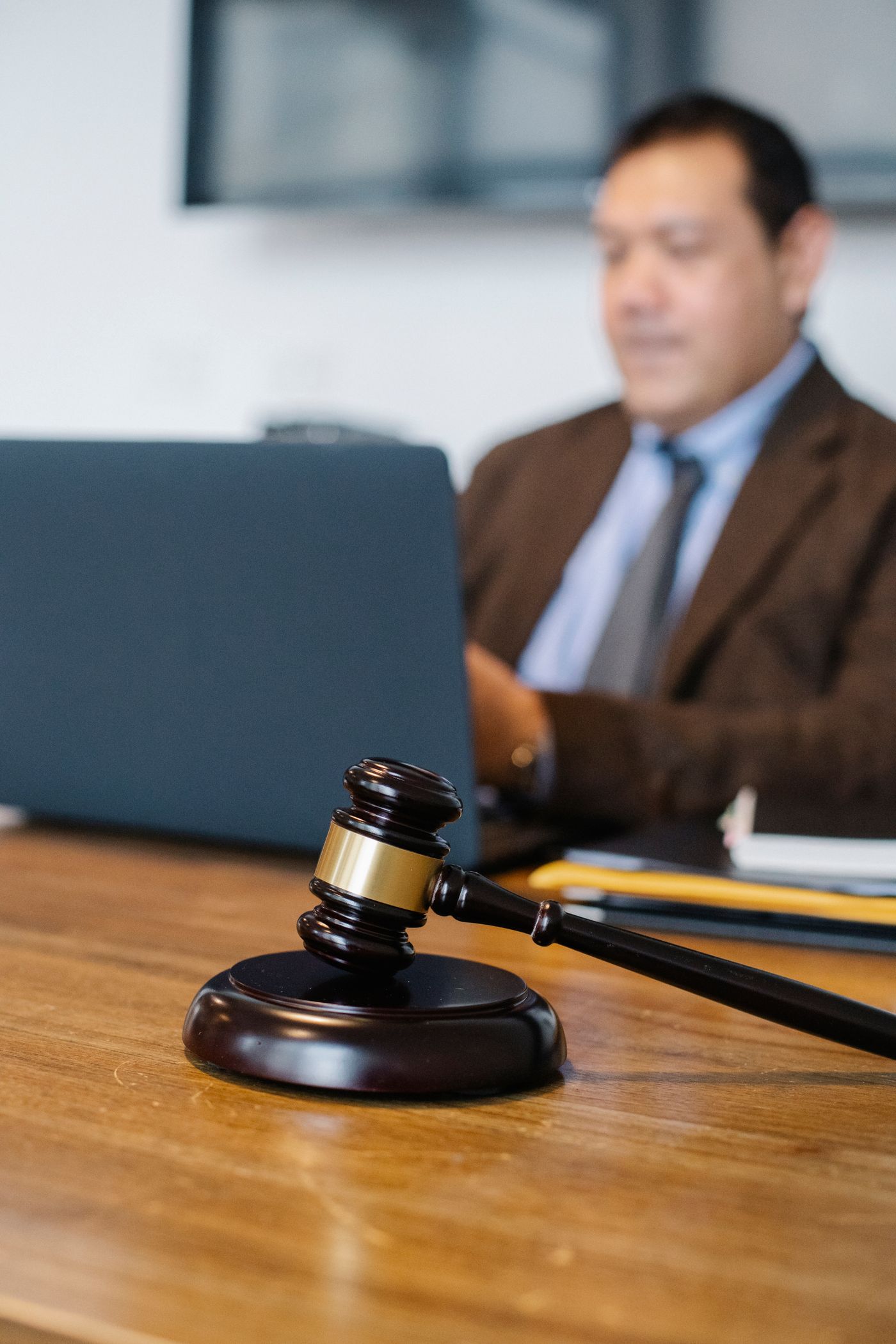 A legal professional works at a laptop beside a courtroom gavel.