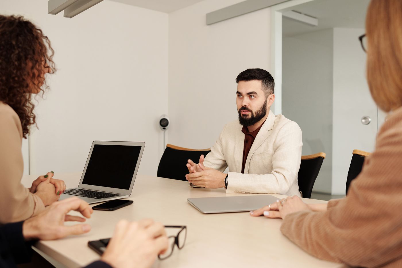 Three adults confer around a laptop at an office table.