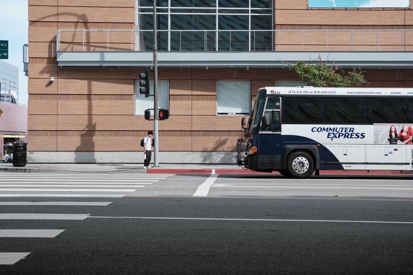 A commuter bus waits at an urban intersection.