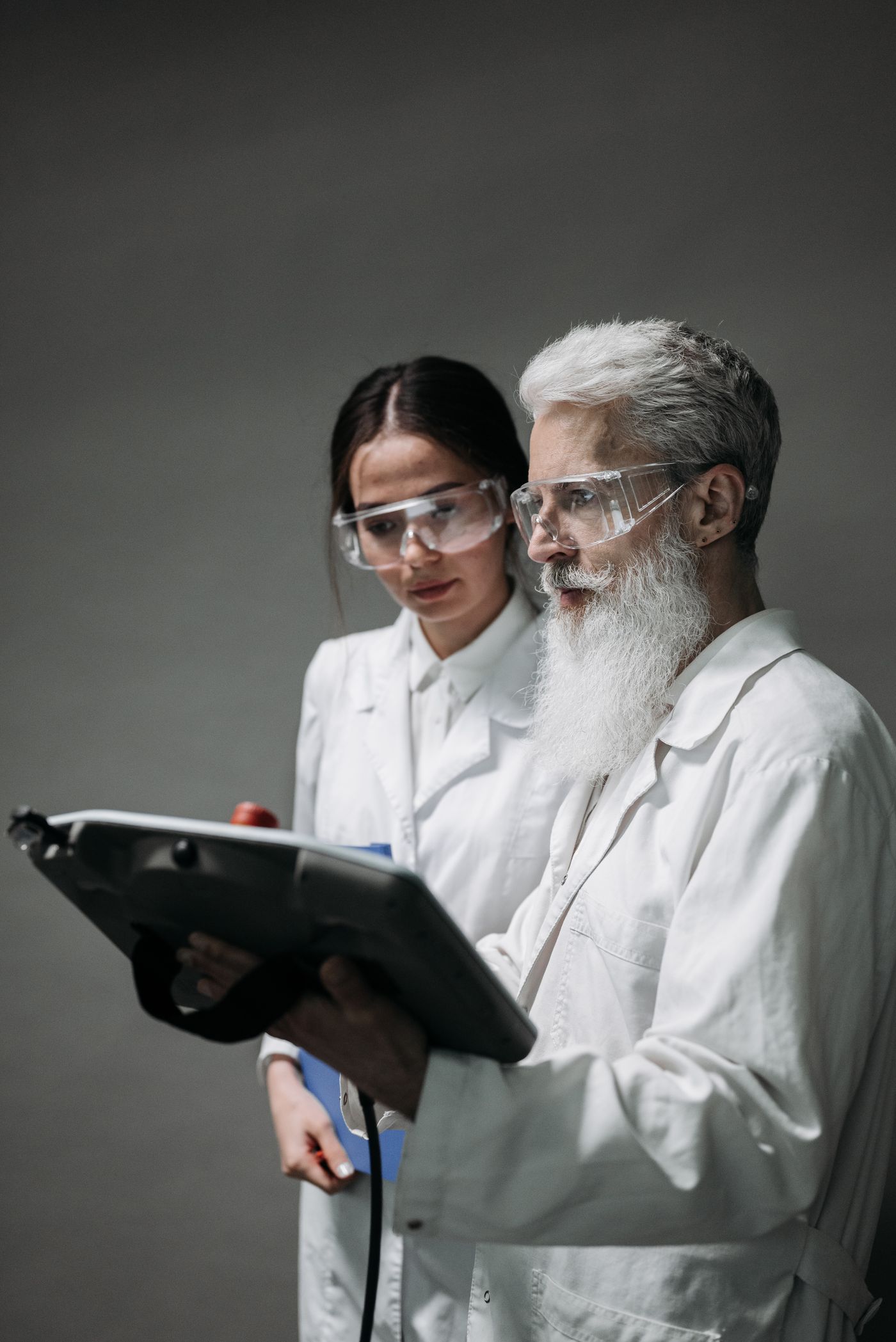 Two scientists review data on a tablet beside laboratory equipment.