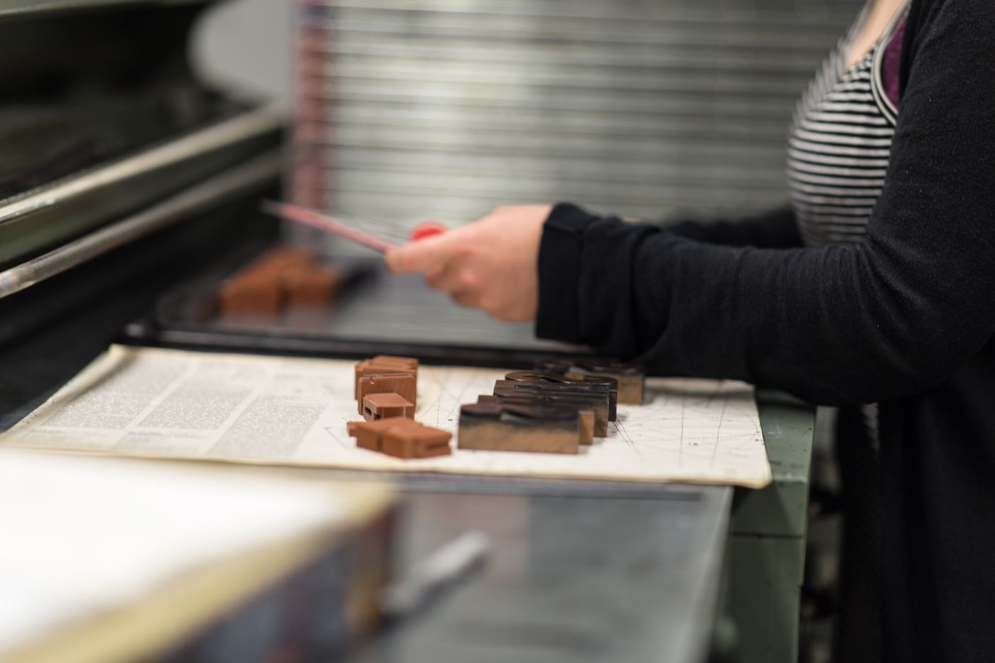 An artist works with wooden printing blocks in a manual workshop.