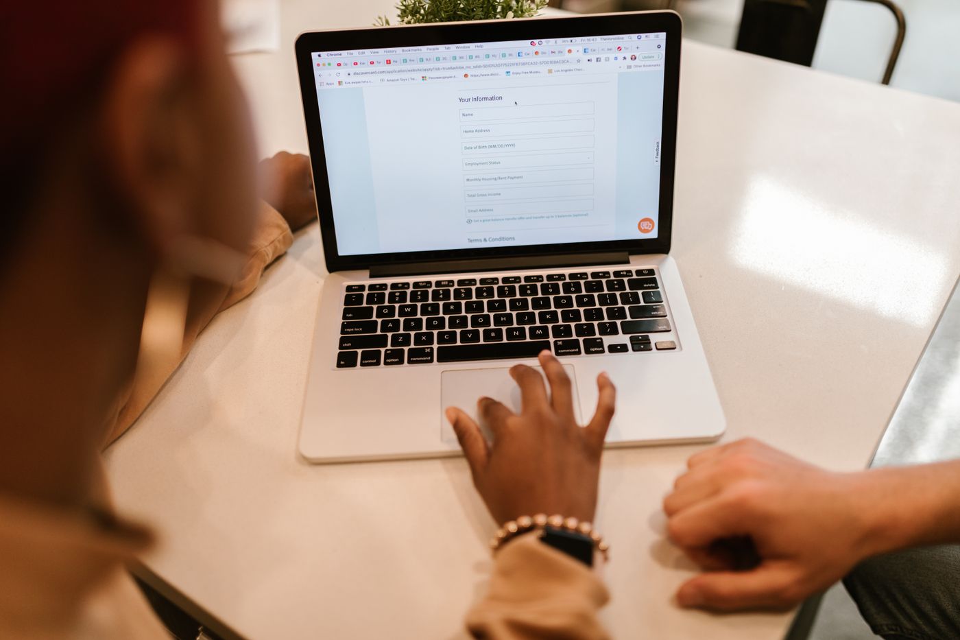Two adults complete an online form on a laptop.