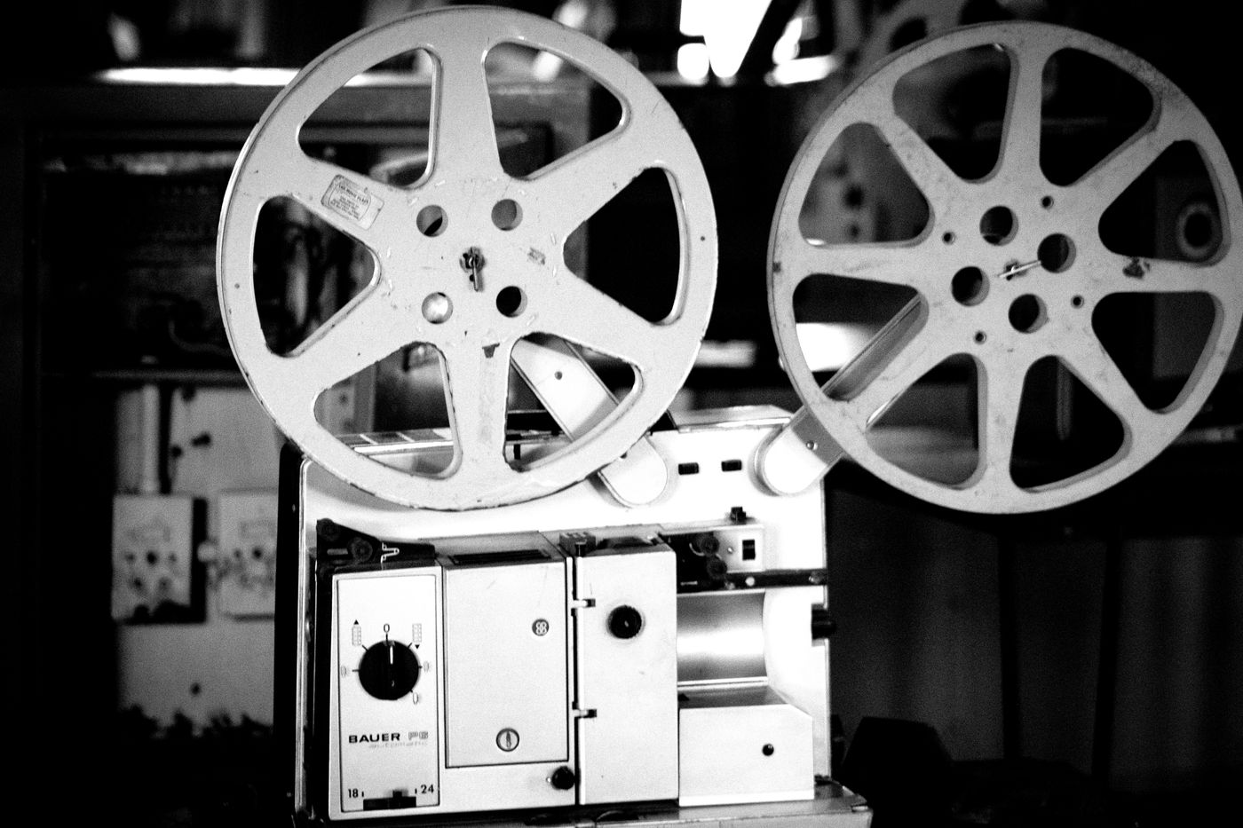 Two film reels sit on a vintage projector in a black-and-white photograph.