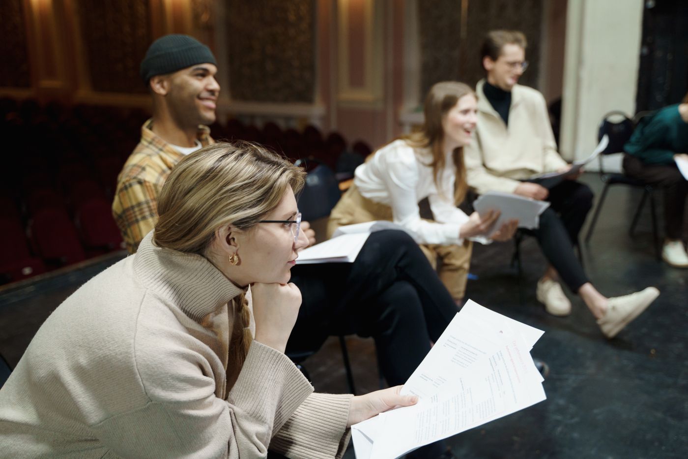 Actors sit with scripts during a theater rehearsal.
