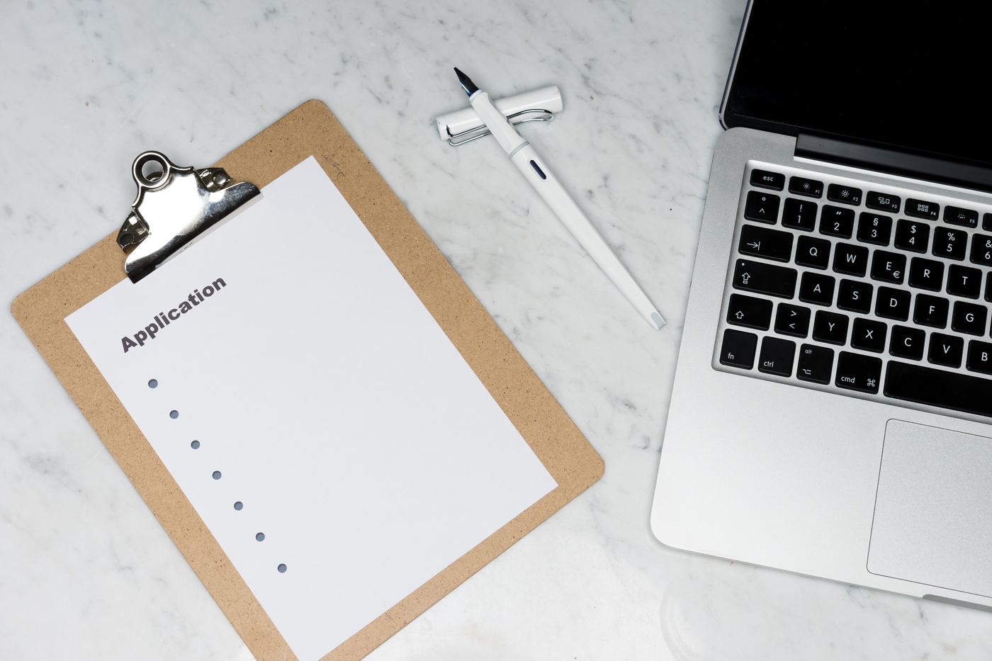 An application clipboard sits beside a laptop and pen.
