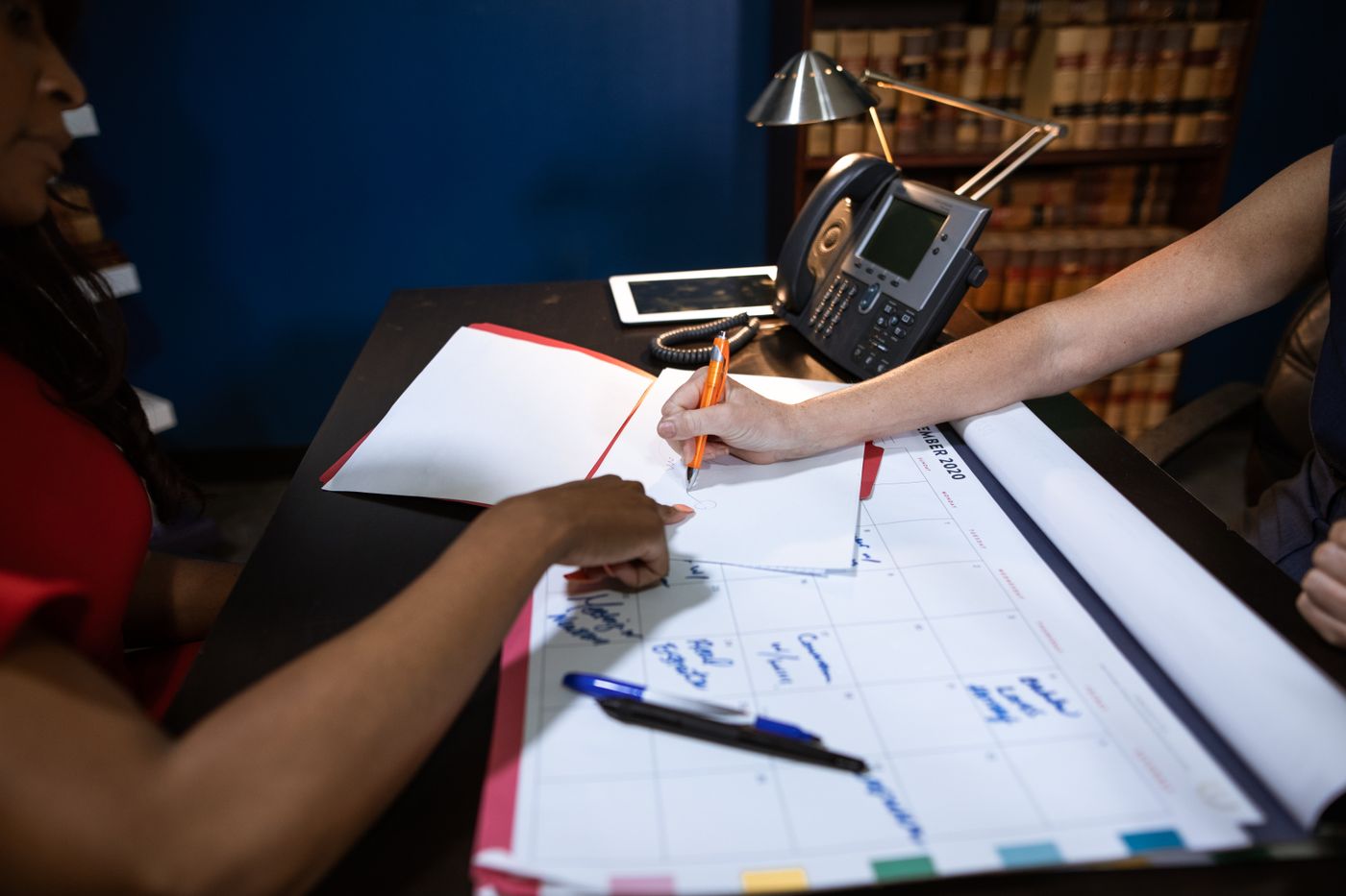 Two people review drawings and make notes at a desk.