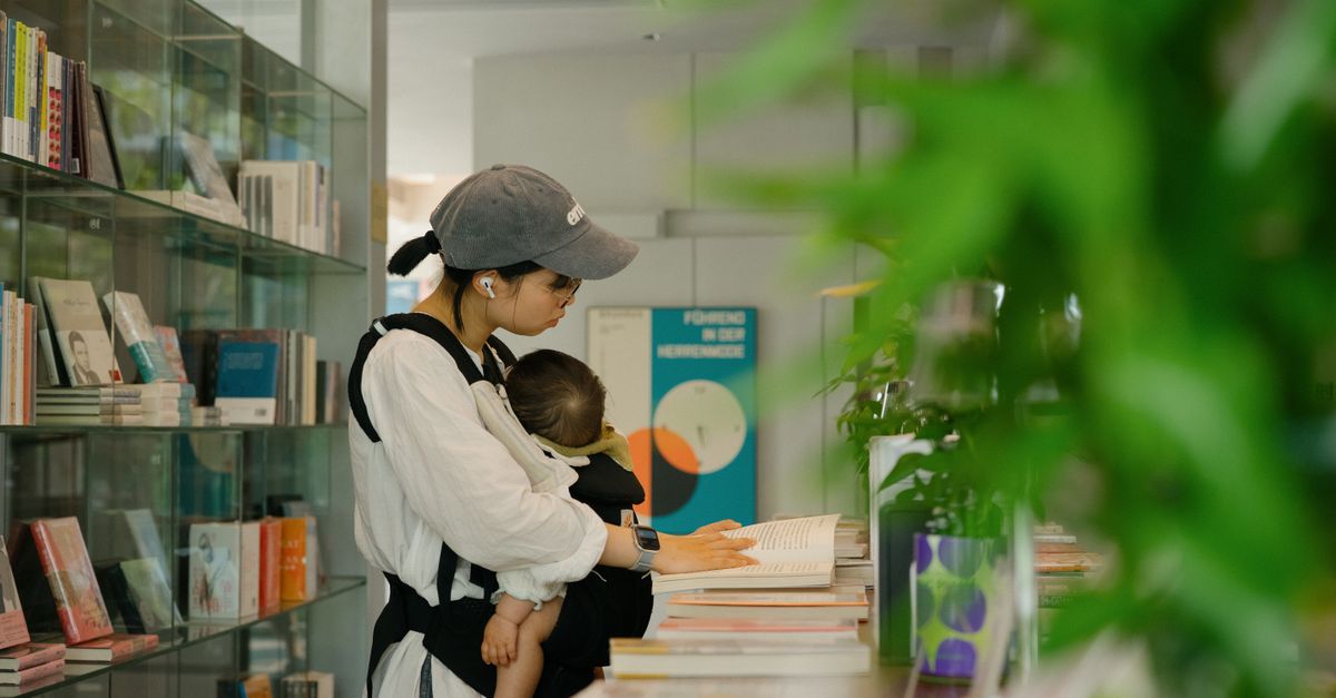 A caregiver and baby browse books in a library.
