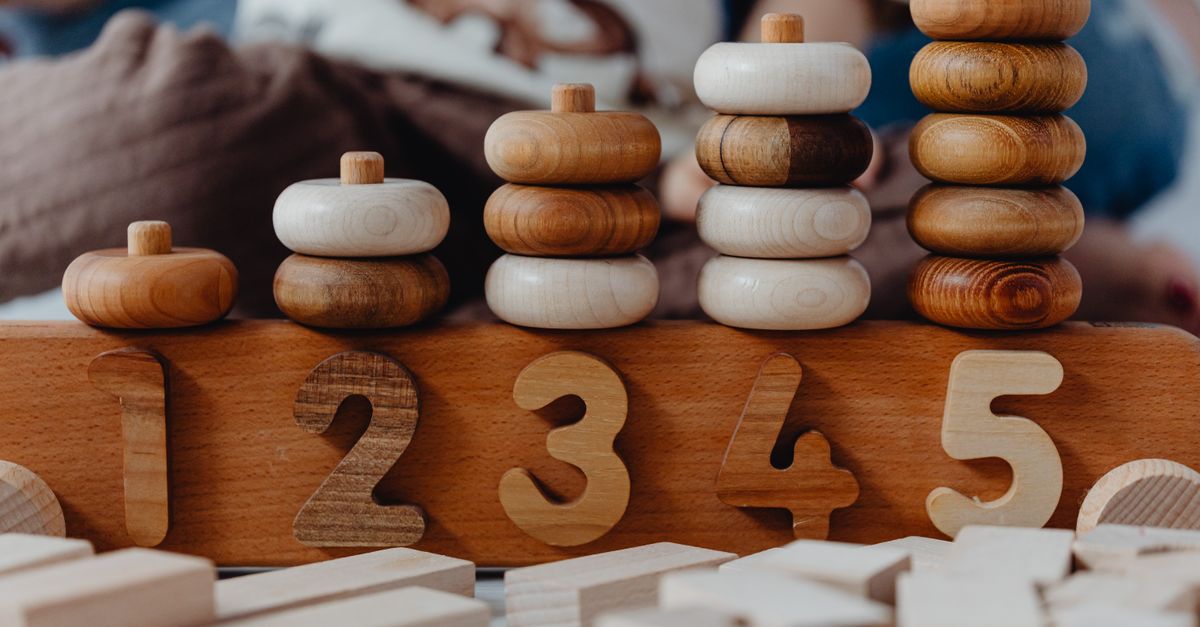 Wooden counting toys and number pieces sit on a table.