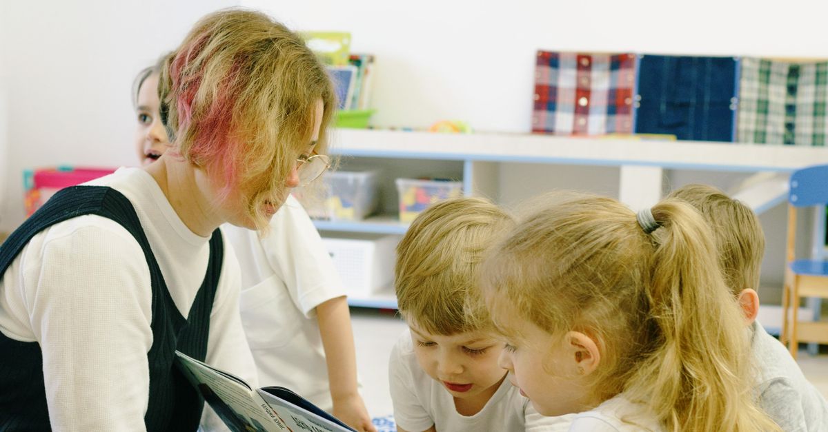A teacher reads with children in a classroom.