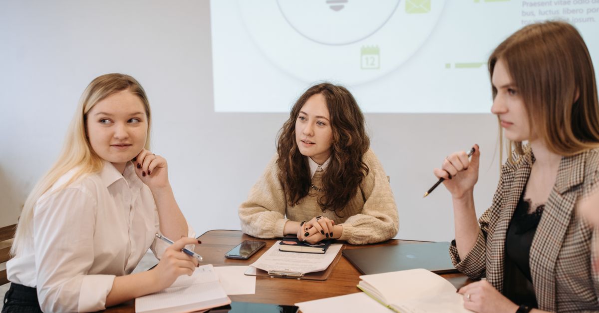 Students discuss ideas around a table.