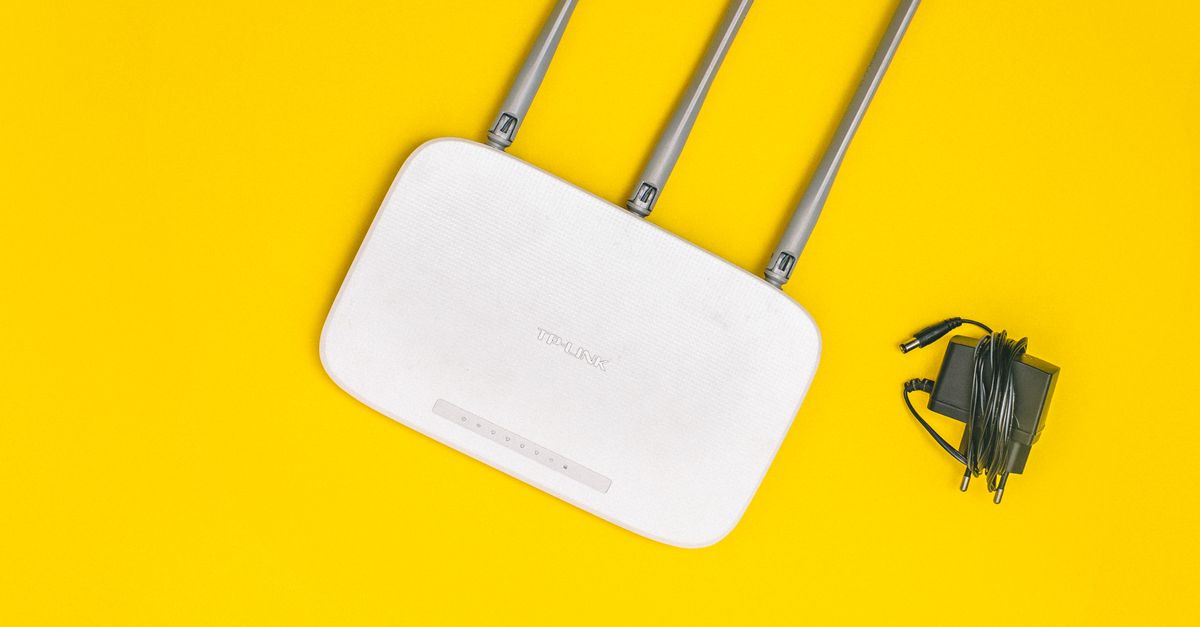 A wireless router rests on a bright yellow surface.