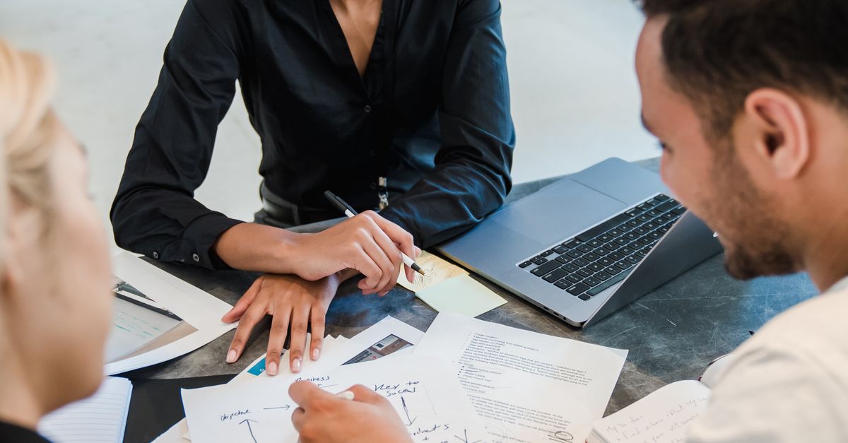 Three adults review documents during an office meeting.