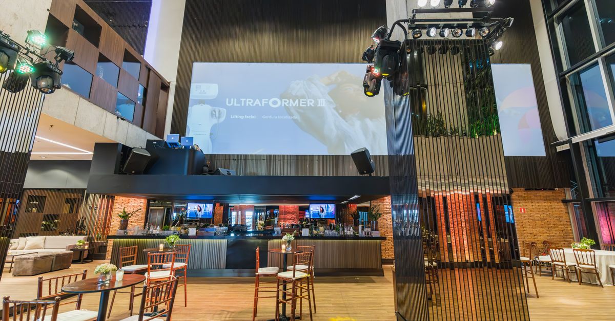 A furnished indoor event venue includes tables, chairs and presentation equipment.